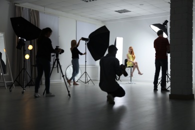 Blurred photo studio with professional equipment and team of workers