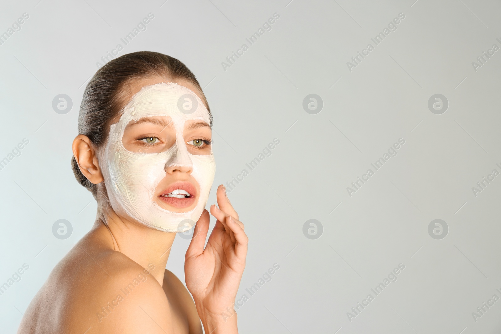 Photo of Beautiful woman with clay mask on her face against grey background. Space for text