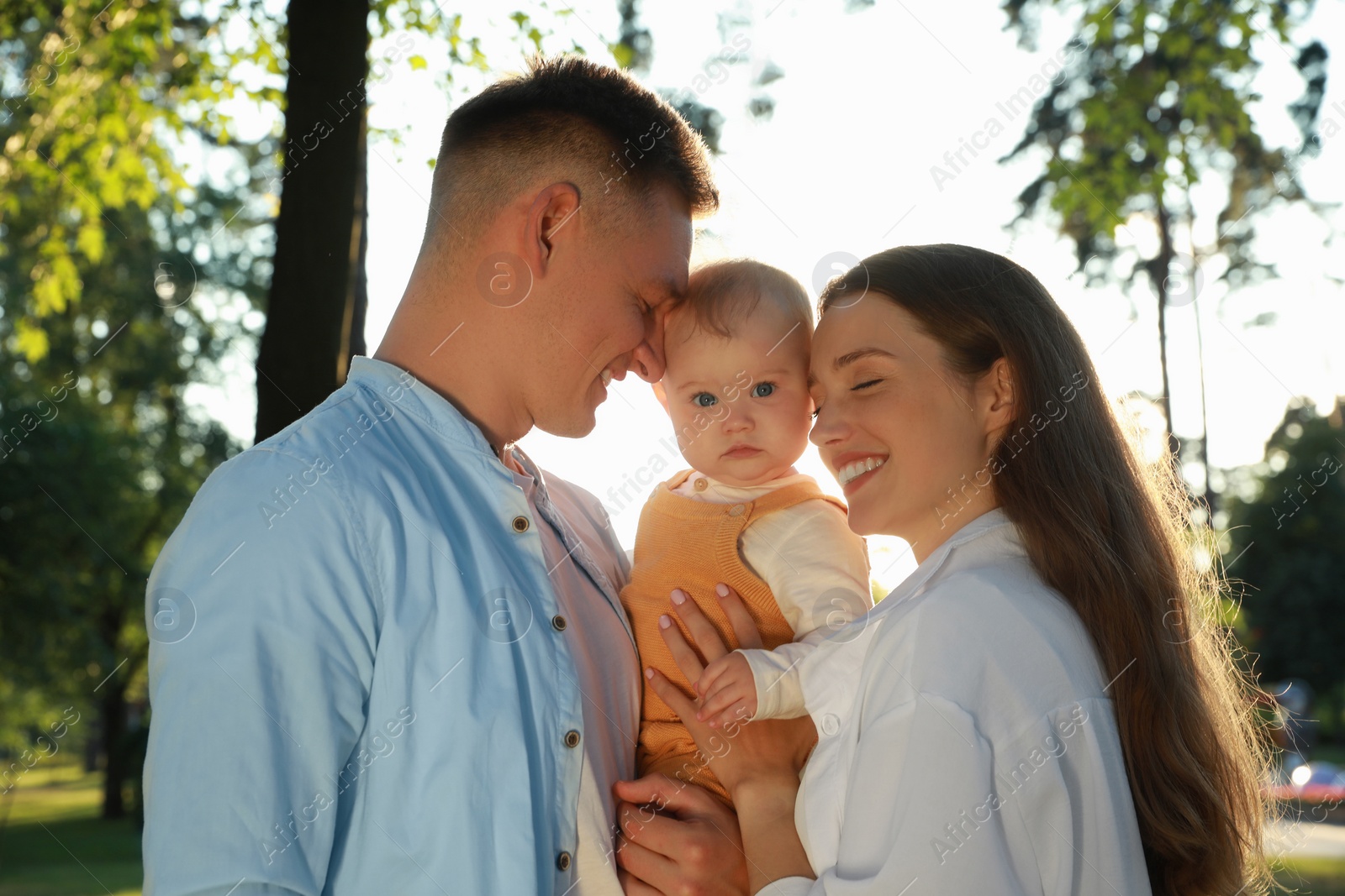 Photo of Parents with their cute daughter spending time together in park on summer day