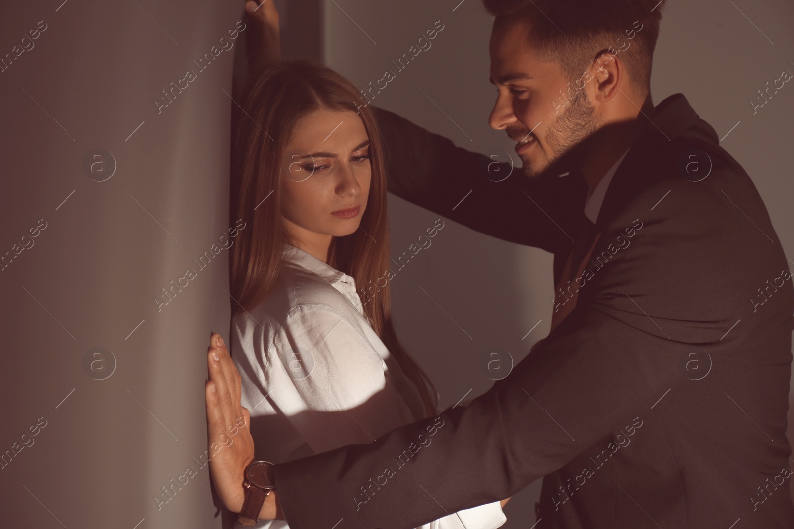 Photo of Boss molesting his female secretary on dark background. Sexual harassment at work