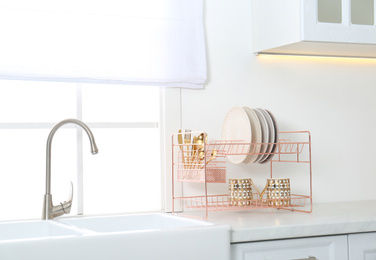 Photo of Clean dishes on drying rack in modern kitchen interior