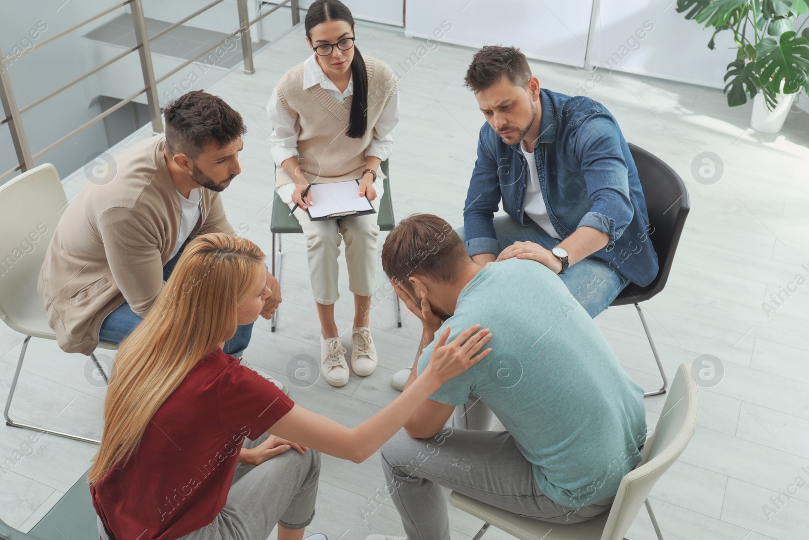 Photo of Psychotherapist working with group of drug addicted people at therapy session indoors