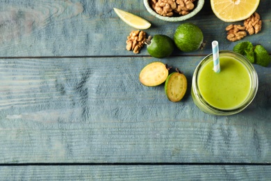 Photo of Fresh feijoa smoothie and fresh ingredients on wooden table, flat lay. Space for text