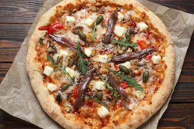 Tasty pizza with anchovies, arugula and olives on wooden table, top view