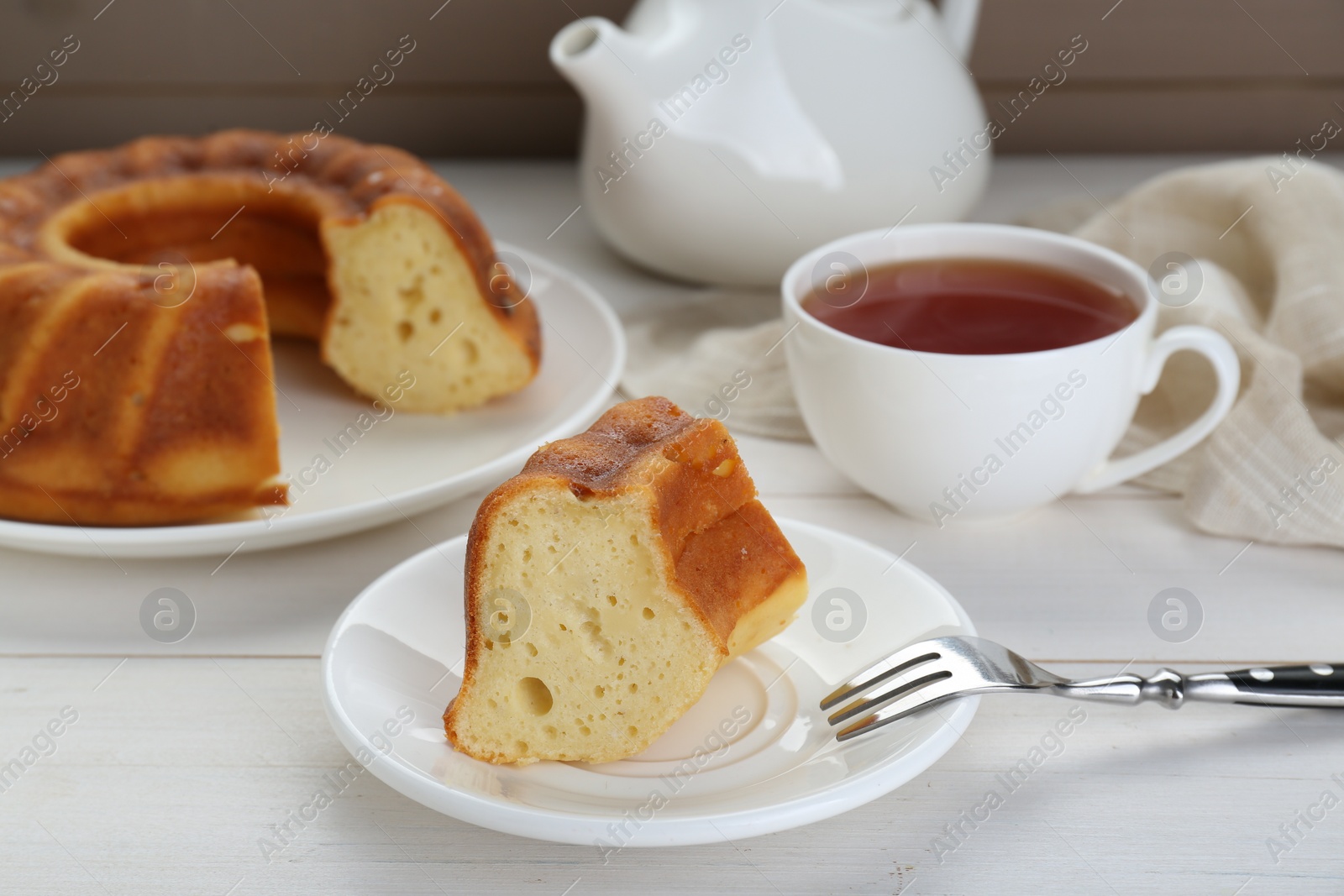 Photo of Piece of delicious homemade yogurt cake served on white wooden table