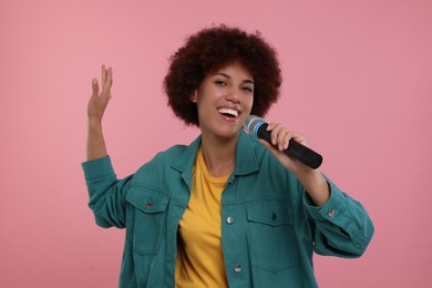 Photo of Curly young woman with microphone singing on pink background