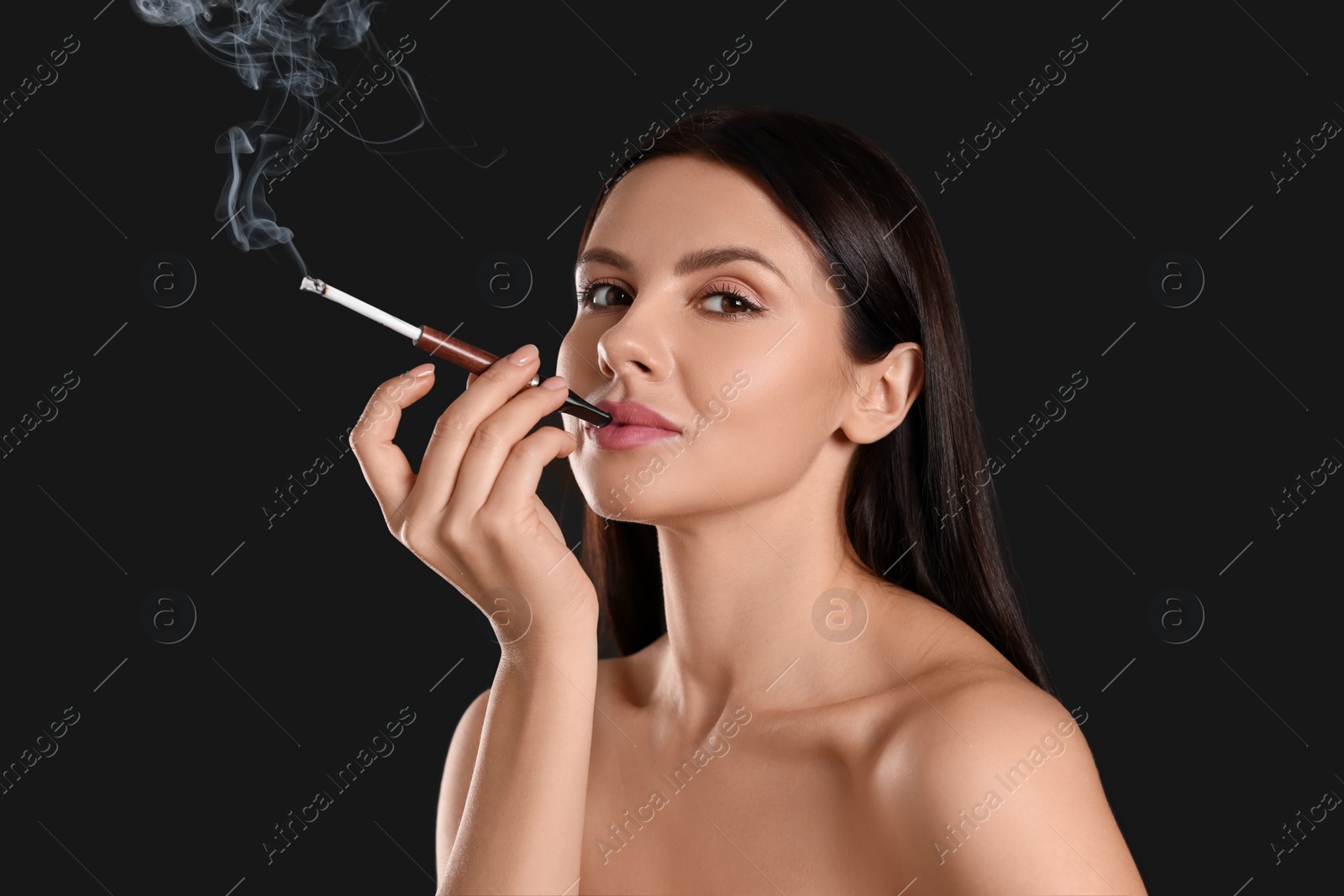 Photo of Woman using long cigarette holder for smoking on black background