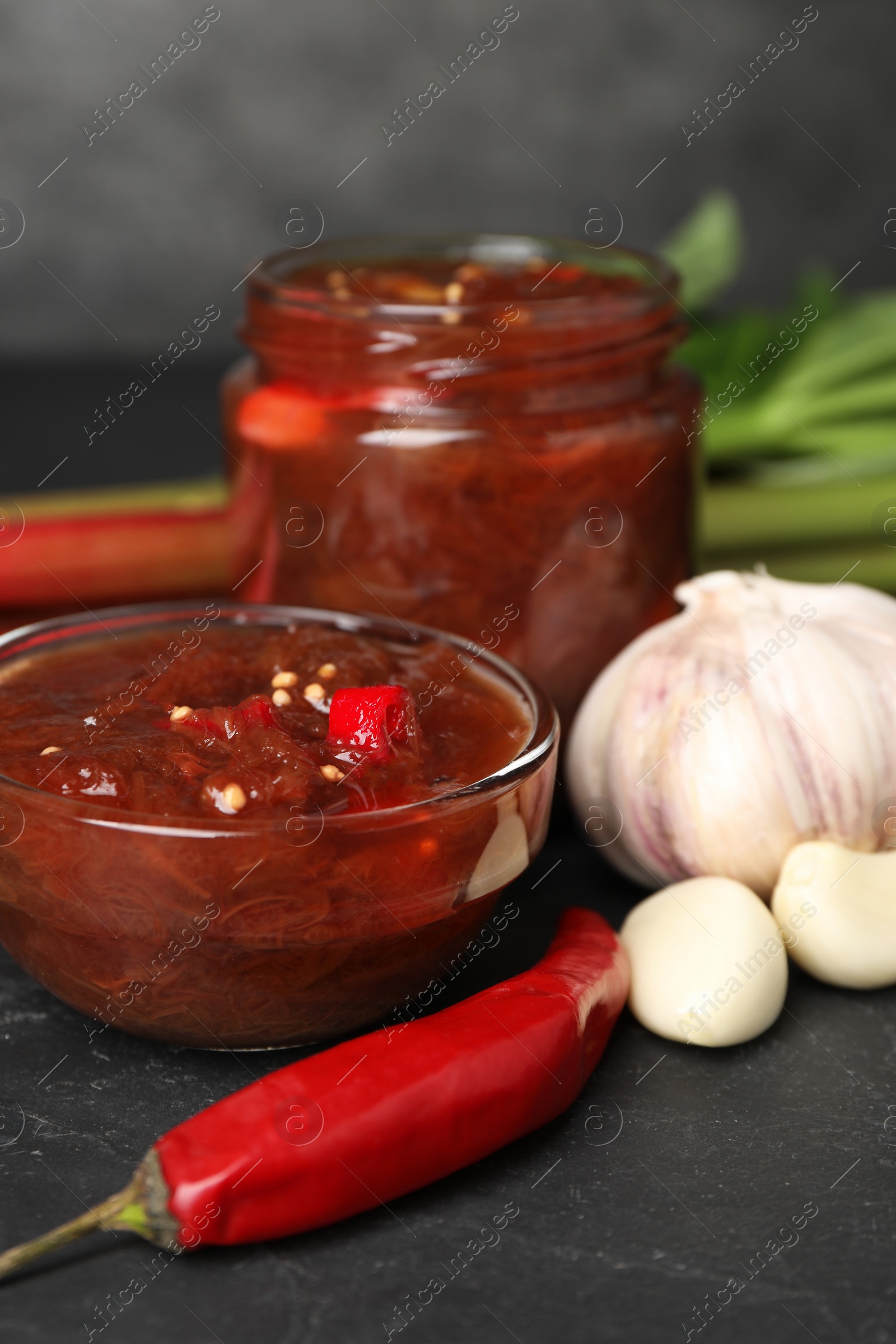 Photo of Tasty rhubarb sauce and ingredients on black table