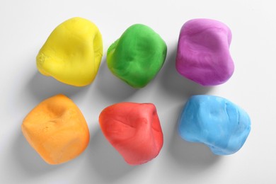 Photo of Different color play dough on white background, top view