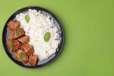 Delicious goulash with rice on green background, top view. Space for text