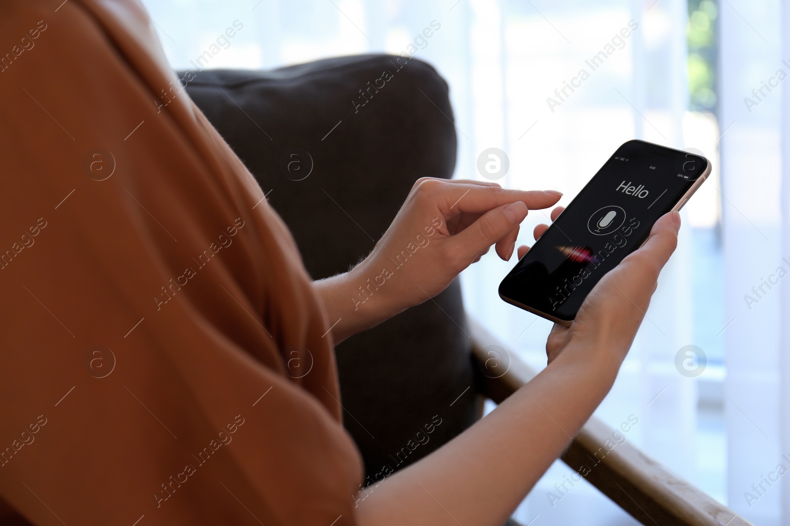 Photo of Woman using voice search on smartphone indoors, closeup