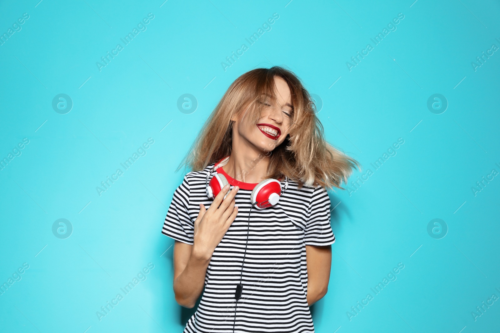 Photo of Beautiful young woman with healthy long blonde hair and headphones on color background