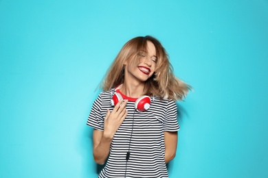 Photo of Beautiful young woman with healthy long blonde hair and headphones on color background