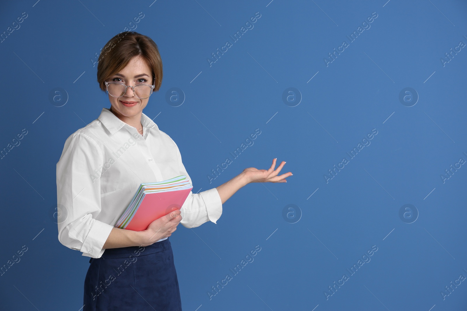 Photo of Portrait of female teacher with notebooks on color background