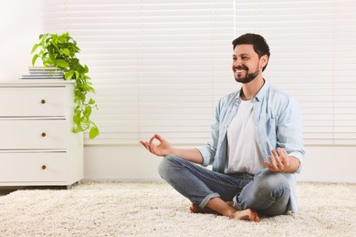 Photo of Man meditating at home, space for text. Harmony and zen
