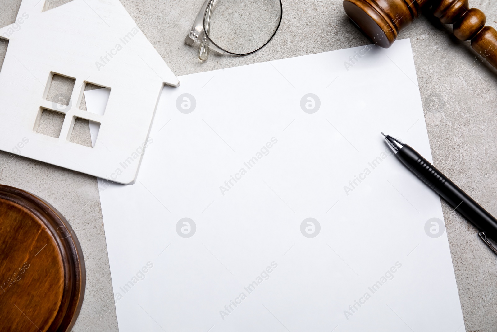 Photo of Last will and testament near house figure, glasses and gavel on light grey table, flat lay