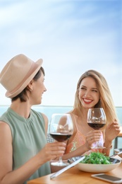 Young women with glasses of wine at table