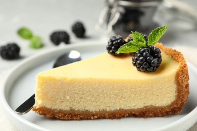 Photo of Piece of delicious cheesecake with blackberries on table, closeup