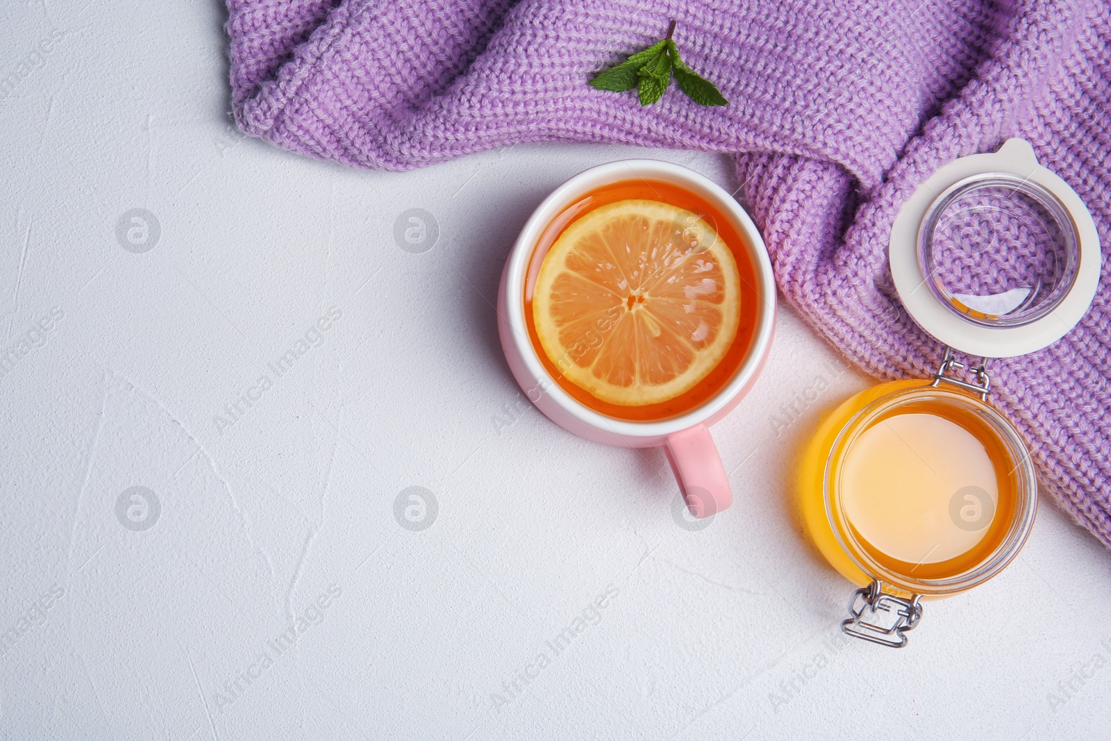 Photo of Cup with hot tea, honey and lemon on light background, top view. Space for text