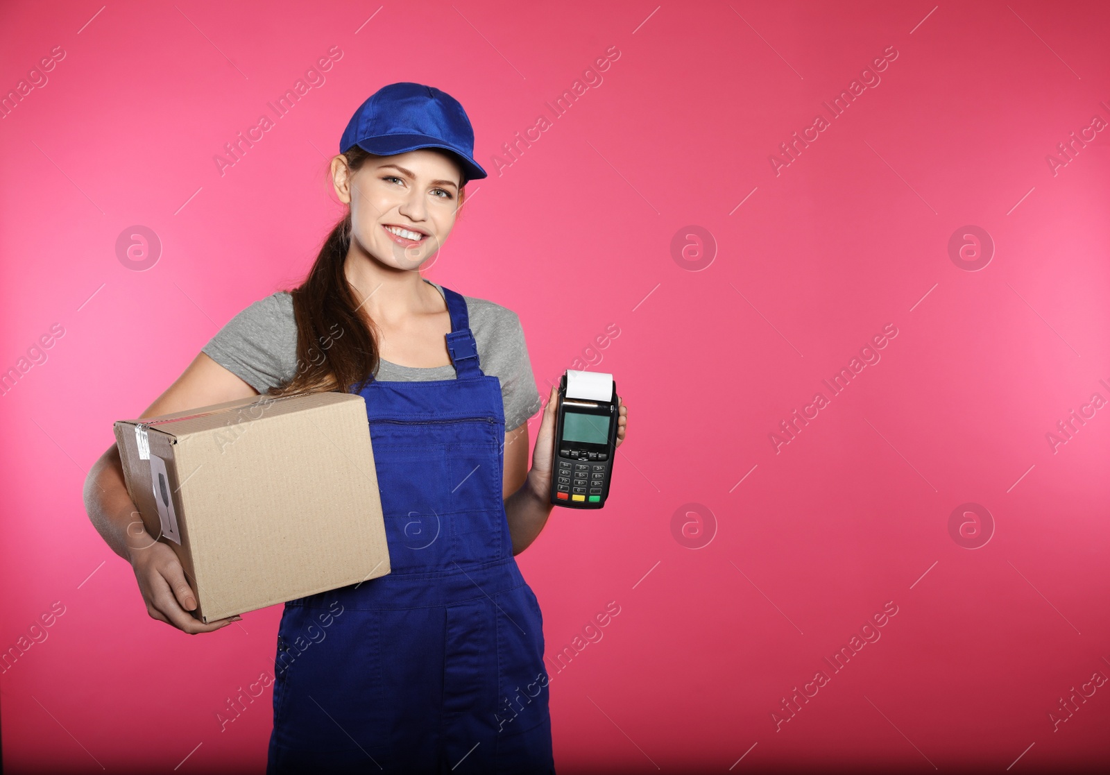 Photo of Smiling courier with payment terminal and parcel on color background. Space for text