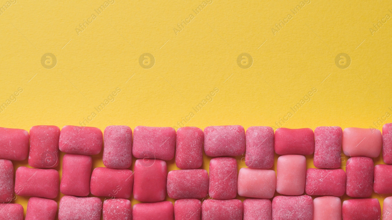 Photo of Sweet chewing gums on yellow background, flat lay. Space for text