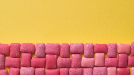 Photo of Sweet chewing gums on yellow background, flat lay. Space for text