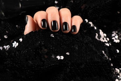 Photo of Woman with black manicure holding shiny fabric, closeup. Nail polish trends
