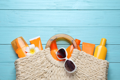 Photo of Sun protection products in bag on light blue wooden background, flat lay. Space for text