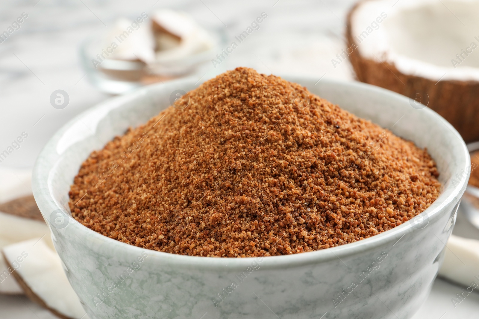 Photo of Natural coconut sugar in ceramic bowl on table, closeup