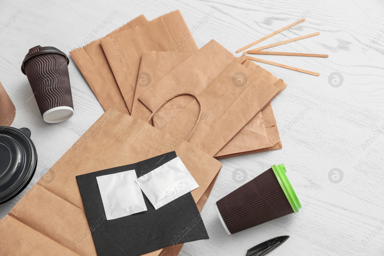 Photo of Paper bags and different takeaway items on wooden background. Space for design
