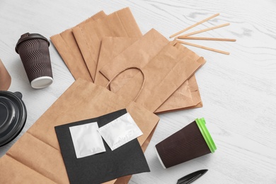 Paper bags and different takeaway items on wooden background. Space for design