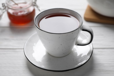 Photo of Cup of fresh tasty tea on white wooden table