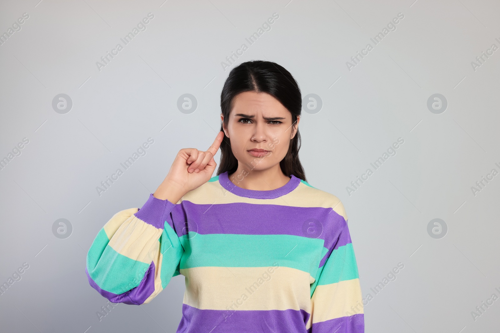 Photo of Young woman suffering from ear pain on light grey background