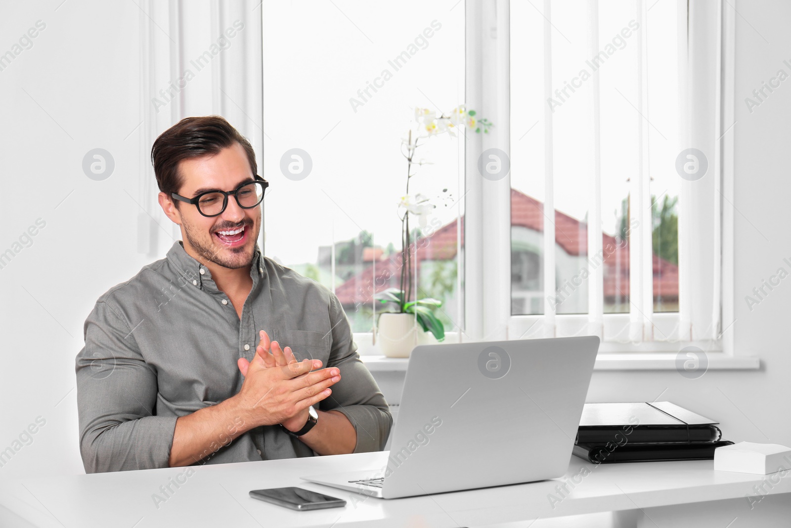 Photo of Handsome young man working with laptop at table in office