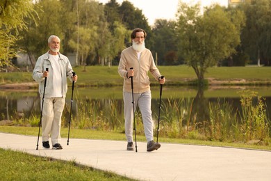 Two senior friends performing Nordic walking outdoors, space for text