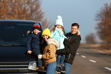 Happy family with little children near modern car on road