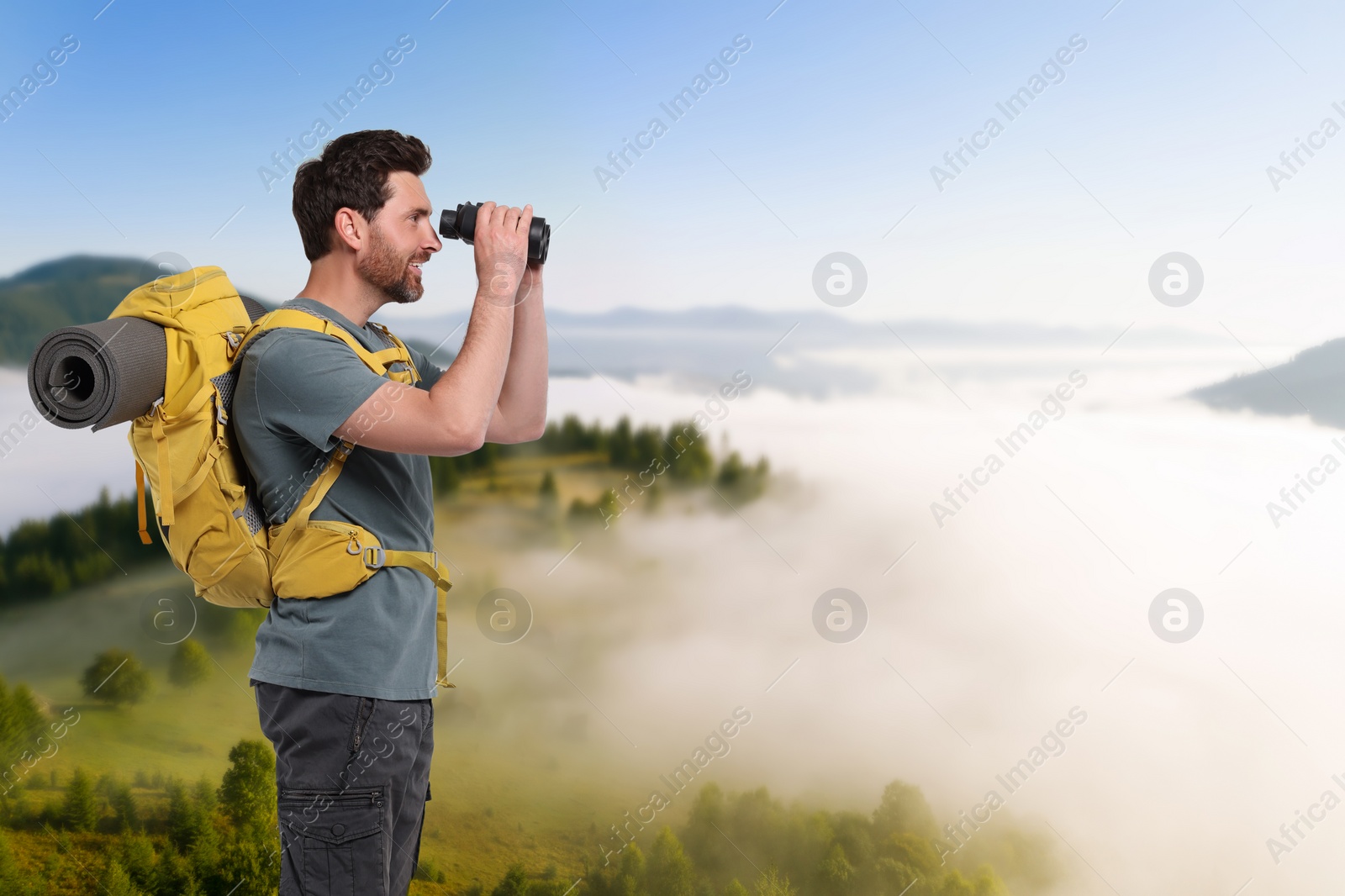 Image of Tourist with backpack and binoculars in mountains