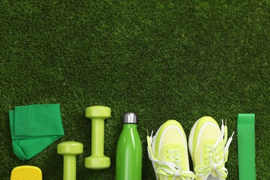 Different sports equipment on green grass, flat lay. Space for text