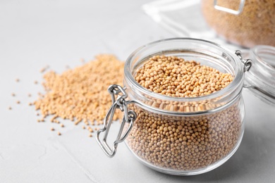 Photo of Mustard seeds with glass jar on light table, closeup. Space for text