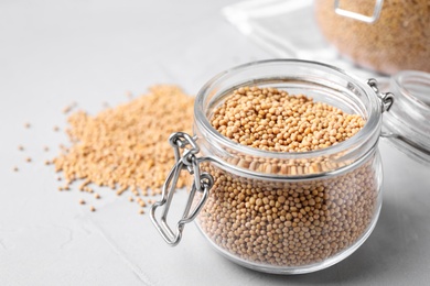 Mustard seeds with glass jar on light table, closeup. Space for text