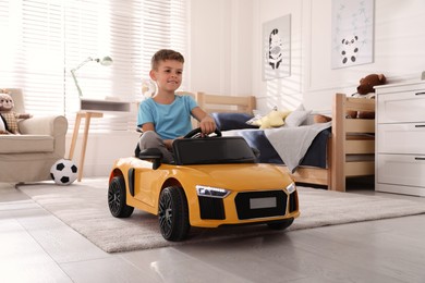 Cute little boy driving big toy car at home