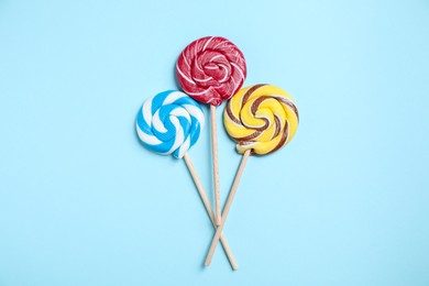 Sticks with colorful lollipops on light blue background, flat lay