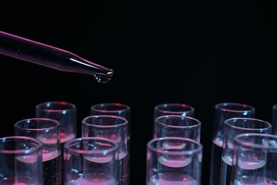 Photo of Dripping reagent into test tube on black background, closeup. Laboratory analysis