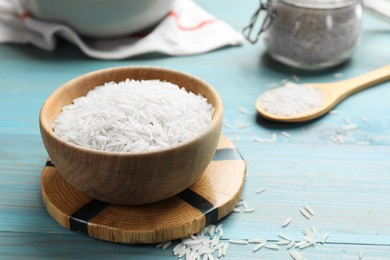 Photo of Raw basmati rice in bowl on light blue wooden table, closeup. Space for text