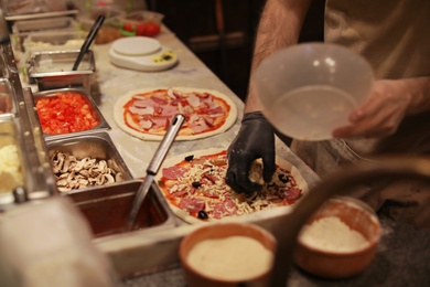 Photo of Man making pizzas at table, closeup view