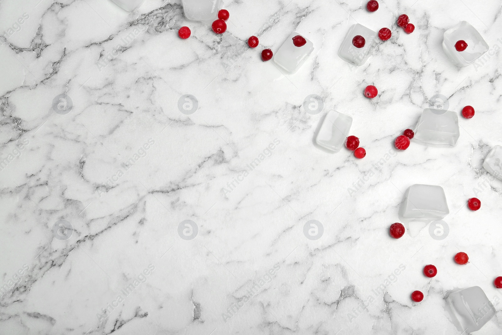 Photo of Frozen berries and ice cubes on marble table, flat lay composition with space for text