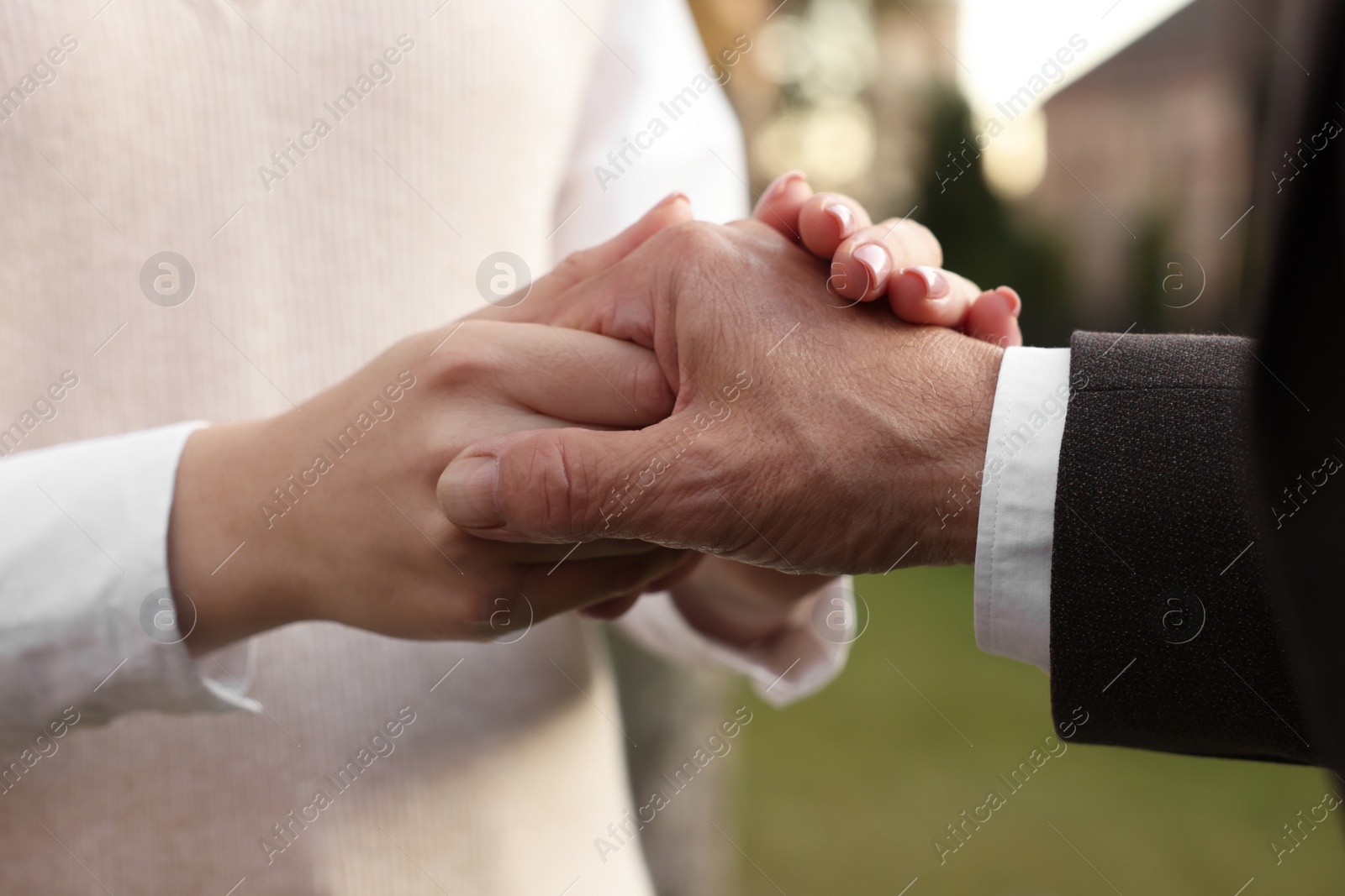 Photo of Trust and deal. Partners joining hands outdoors, closeup