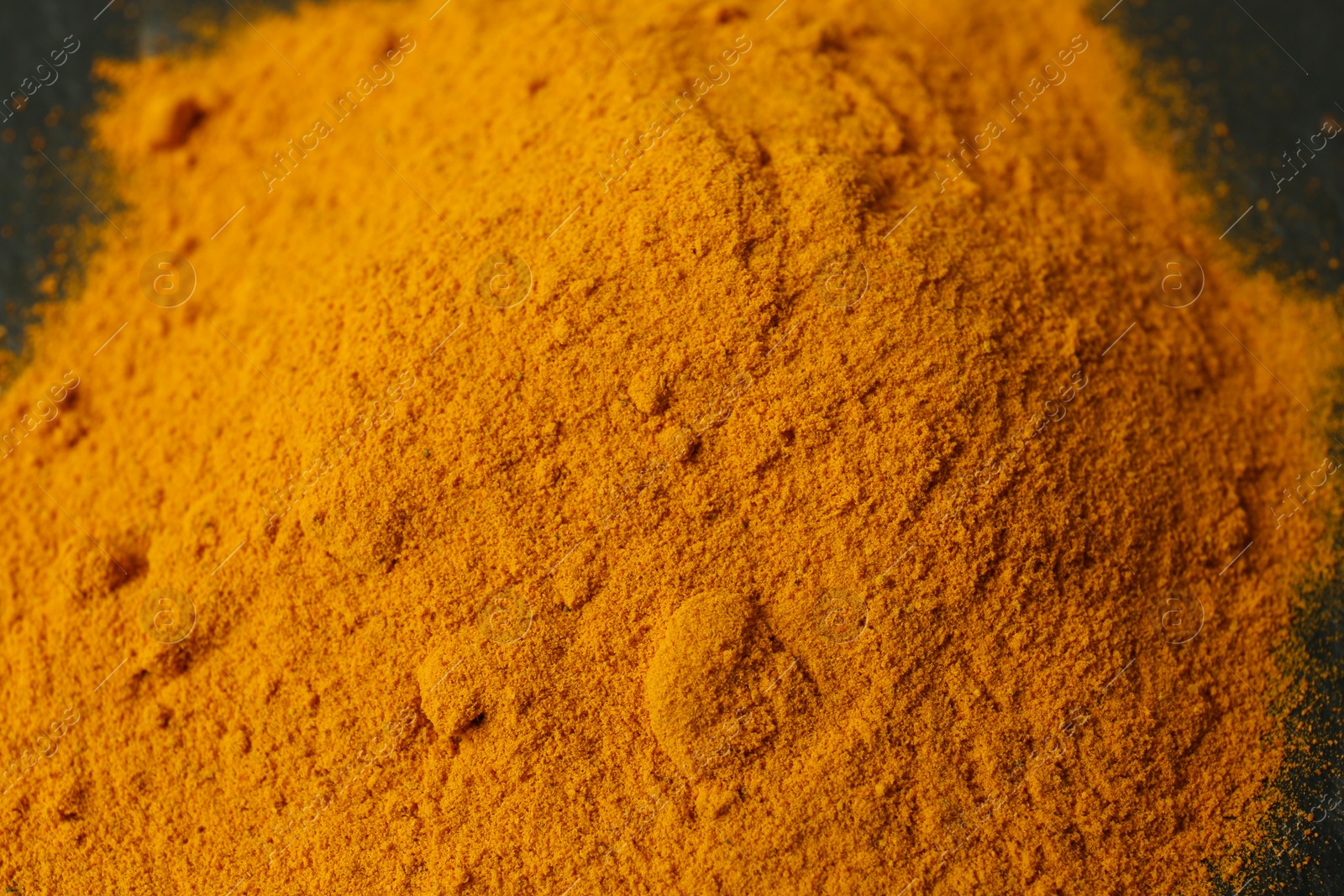 Photo of Aromatic turmeric powder on black table, closeup