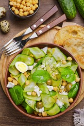 Photo of Delicious cucumber salad and toasted bread served on wooden table, flat lay