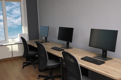 Open office interior. Modern workplaces with computers near light grey wall